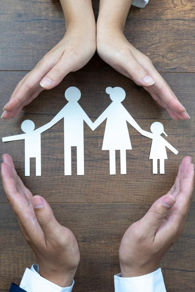 Helping hands over a paper cutout of a family